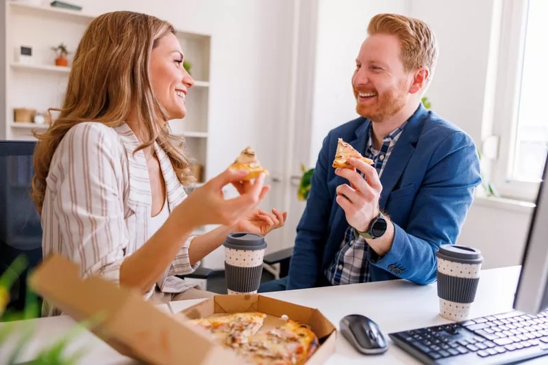 funcionários a comerem no escritório uma refeição fast food que pagaram com o cartão refeição da Pluxee