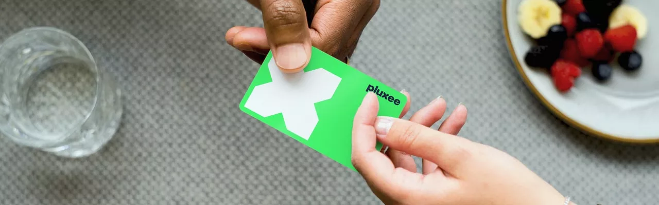 cartão refeição da pluxee sendo segurado por duas mãos diferentes