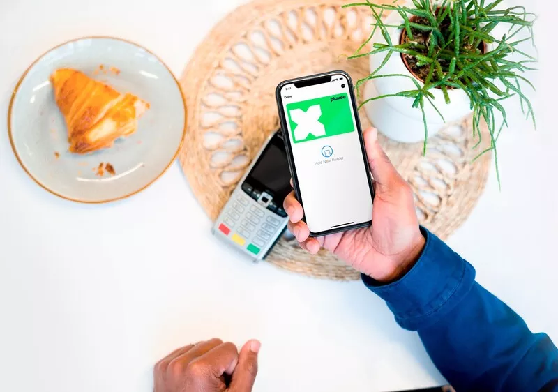 uma mão a segurar um telemóvel com a aplicação do cartãorefeição aberta para pagar a conta