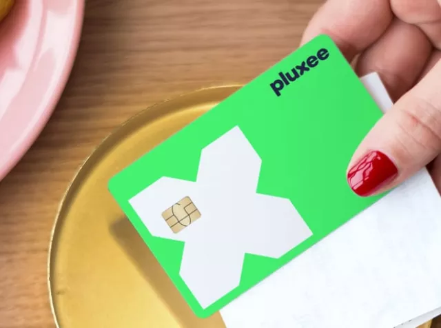 a mão de uma mulher a segurar o cartão refeição da pluxee