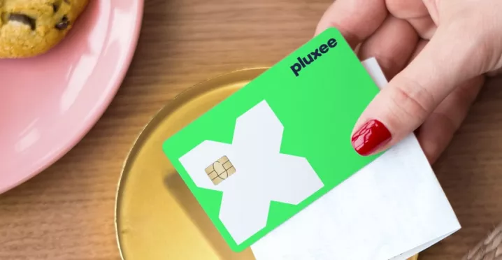 a mão de uma mulher a segurar o cartão refeição da pluxee