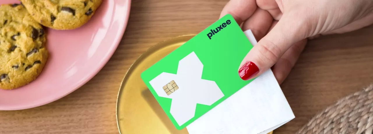 a mão de uma mulher a segurar o cartão refeição da pluxee