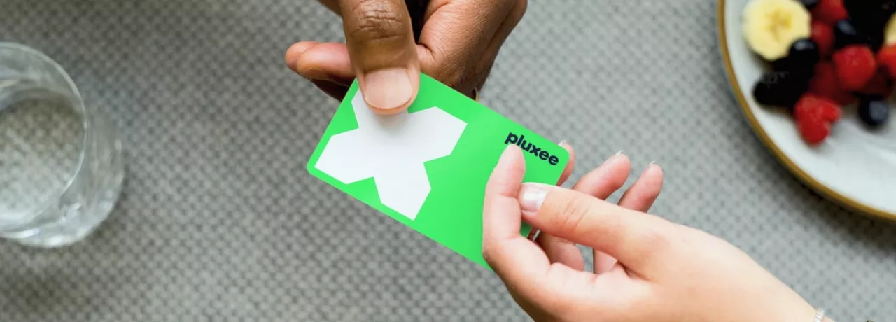 cartão refeição da pluxee sendo segurado por duas mãos diferentes
