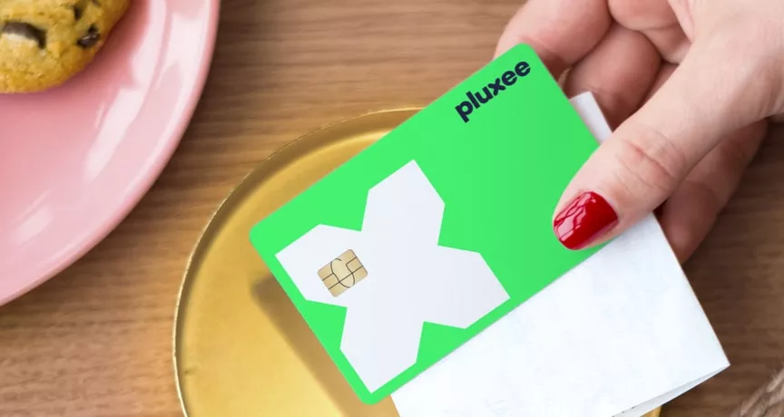 a mão de uma mulher a segurar o cartão refeição da pluxee