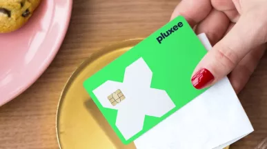 a mão de uma mulher a segurar o cartão refeição da pluxee